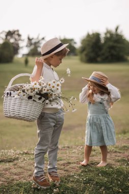 A handsome boy in a hat and a white t- shirt in suspenders with 