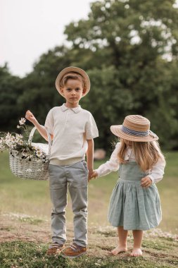 A handsome boy in a hat and a white t- shirt in suspenders with 