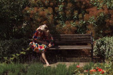 Genç anne küçük kızıyla gül bahçesinde oturuyor..