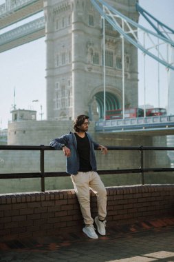 Londra 'daki Hintli yakışıklı adam Londra Köprüsü' nün karşısında. Londra Köprüsü ve Londra kırmızı otobüsü. Yüksek kalite fotoğraf