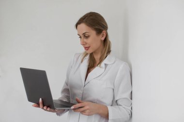Modern teknoloji dizüstü bilgisayarla çalışan profesyonel doktor hanımın fotoğrafı. Hasta reçeteli notları yazıyor. Stetoskop beyaz önlük giyiyor. Yüksek kalite fotoğraf
