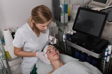 Güzel kız spa salonunda gençleşme karşıtı bir prosedür uyguluyor. Zevkle yalan söylüyor. Güzellik uzmanı lazeri yanağına doğru kaldırıyor. Yüksek kalite fotoğraf
