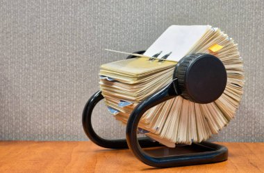 Rolodex dosya düzenleyicisi bir ofis masasında açık duruyor, gri bölme bölümünün arkasındaki açılı görünüm.