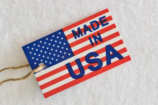 Made in USA label sitting on top of white clothing as a business economics concept. Flat lay plain background macro image.