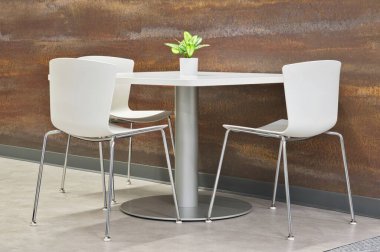 Çağdaş iç tasarım, beyaz masa ve sandalyeli ve uzun metrajlı duvarın yanındaki yapay bitki. Mutfak ve ofis mobilyaları..