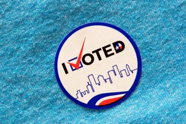 I Voted sticker on a blue shirt indicating Democrat party. Isolated directly above image, political concept. clipart