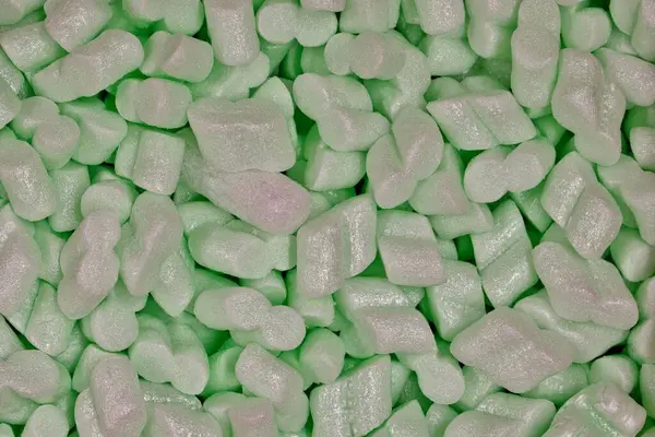 Green packing foam peanuts Styrofoam popcorn packaging noodles material closeup, Polystyrene cushioning protection shipping merchandise.