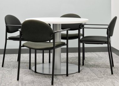 Round table four black chairs furniture in office setting gray carpet no people. clipart
