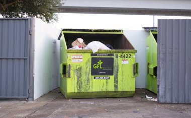 Houston, Texas USA 11-24-2024: Dumpster in fenced enclosure Green For Life company. clipart