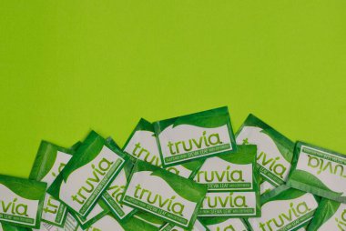Houston, Teksas ABD 05-14-2025: Truvia yapay tatlandırıcı paketleri stevia yaprağı yeşil arkaplan kopyalama alanına saçıldı.