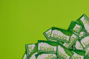 Houston, Teksas ABD 05-14-2025: Truvia yapay tatlandırıcı paketleri stevia yaprağı yeşil arkaplan kopyalama alanına saçıldı.