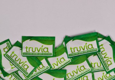 Houston, Teksas ABD 05-14-2025: Truvia yapay tatlandırıcı paketleri stevia yaprağı beyaz arkaplan fotokopi alanına saçıldı.