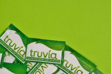 Houston, Teksas ABD 05-14-2025: Truvia yapay tatlandırıcı paketleri stevia yaprağı yeşil arkaplan kopyalama alanına saçıldı.