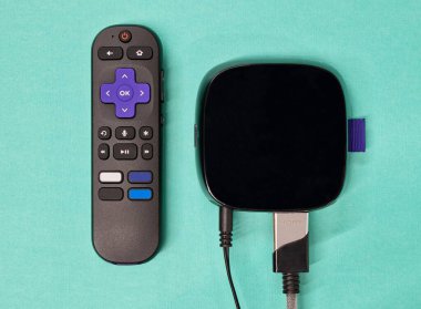 Mavi arkaplan üzerinde uzaktan kumandalı canlı ortam oynatıcı yatıyordu.