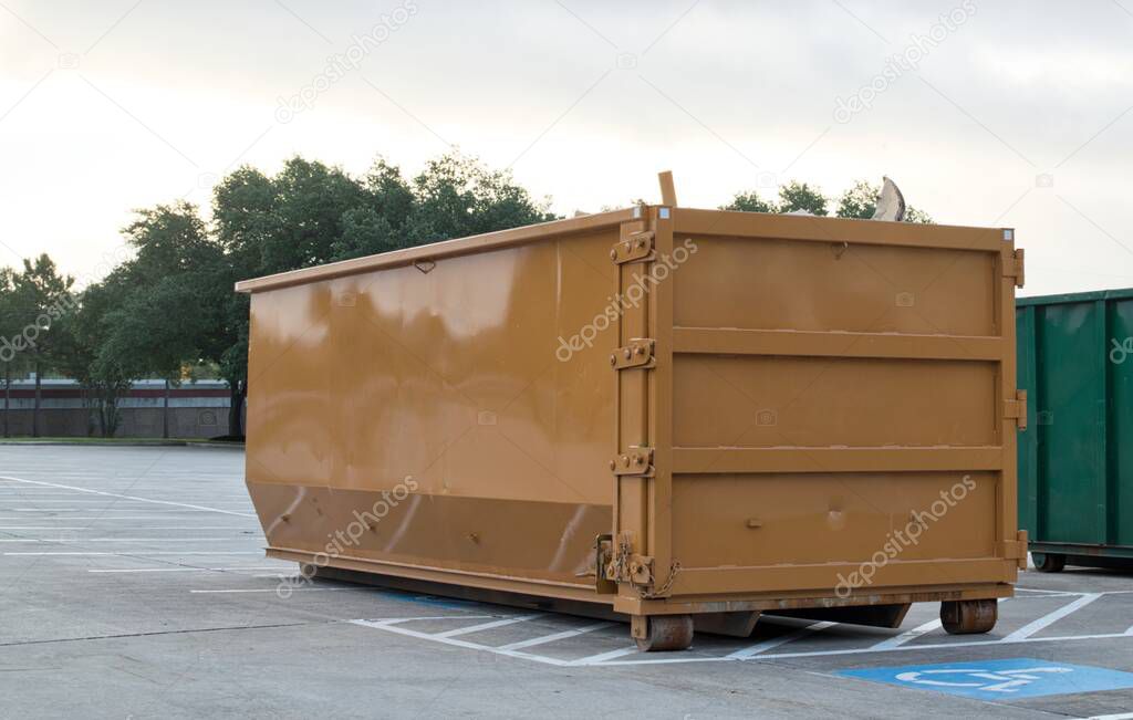 Dumpster rental industrial bin in commercial parking lot site brown trash removal skip.