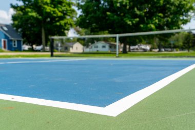 Pickleball ya da tenis kortunun Amerika 'daki eğlence amaçlı sporu, arka planı bulanık yeşil ve mavi kortlu.