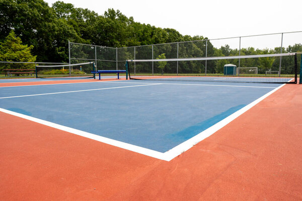 Recreational sport of pickleball or tennis court in the United States with orange and blue court with open background.