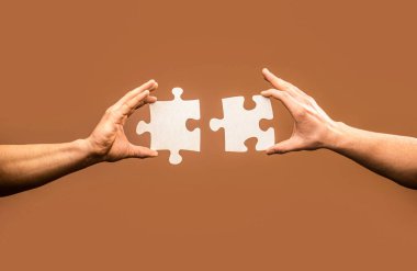Two hands trying to connect couple puzzle piece on gray background. Teamwork concept. Closeup hand of connecting jigsaw puzzle. Holding puzzle. Business solutions, success and strategy concept.
