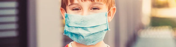 Child wearing a medicine mask outdoors. Coronavirus epidemic. Boy with protection facemask.
