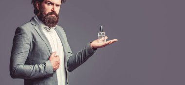 Erkeksi parfüm, takım elbiseli sakallı adam. Elinde parfüm şişesi tutan bir erkek..