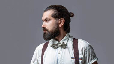 Beard man in bow tie and suspenders. Male in shirt correcting his colorful tie. Portrait of handsome bearded man in white shirt and bow tie, suspenders. Close-up of a gentleman his bowtie.