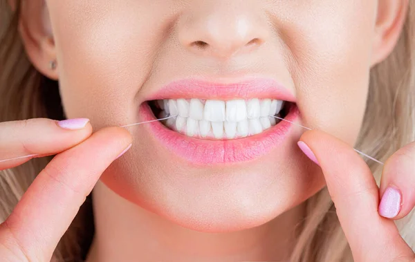 Dental flush - woman flossing teeth. Dental floss. Taking care of teeth. Healthy teeth concept. Teeths Flossing. Oral hygiene and health care. Smiling women use dental floss white healthy teeth.