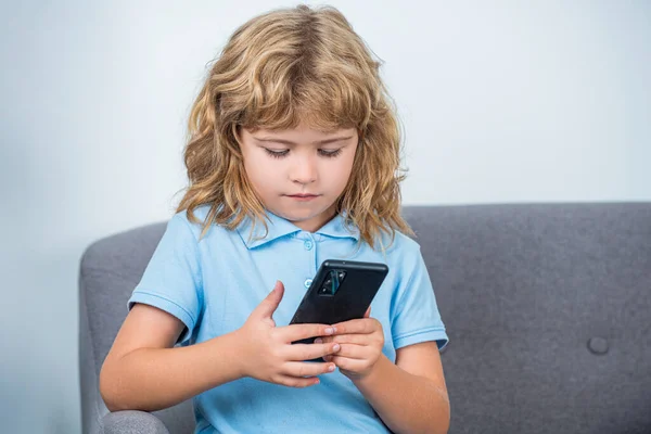 Boy communicates on Internet. Child gadget addiction, insomnia. Little boy using smartphone, looking at screen, child holding phone in hands, playing mobile device game, watching cartoons online.