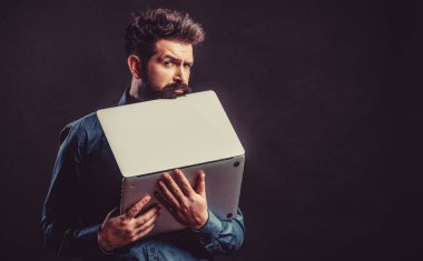 Businessman using his laptop, pc. Bearded male businessman holding a computer in his hands isolated on black background.