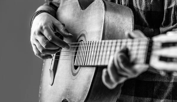 Close up hand playing guitar. Guitars acoustic. Male musician playing guitar, music instrument. Mans hands playing acoustic guitar, close up. Acoustic guitars playing. Black and white.