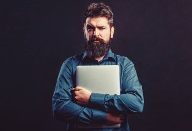 Bilgisayarını kullanan bir iş adamı. Dizüstü bilgisayarı tutuyorum. Gerçekten yakışıklı, sakallı, işçi dizüstü bilgisayar. Sakallı erkek işadamı elinde bilgisayar tutuyor..