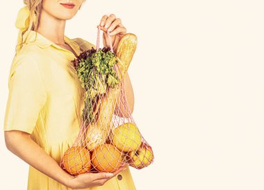 Pamuk eko çanta tutan kız organik meyve, sebze. Çevre dostu ip tutan bir kadın. Yeniden kullanılabilir ağ torbası, meyve, sebze. Sağlıklı, besleyici ve vejetaryen yiyeceklerin içeriği.