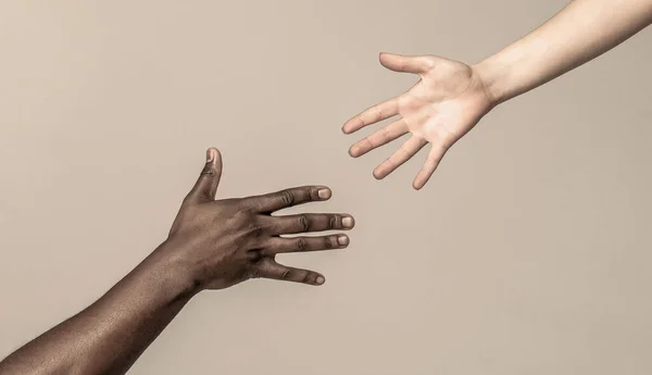 Helping hands, Rescue gesture. Black and white human hands. African and caucasian hands. Giving a helping hand to another.
