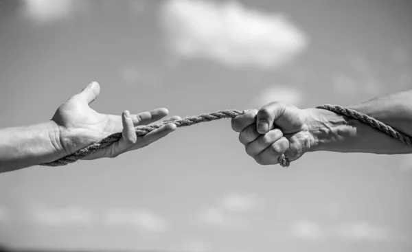 Conflict tug of war. Hand holding a rope, climbing rope, strength and determination. Rescue, help, helping gesture or hands. Black and white.