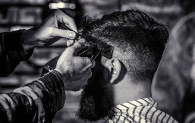 Saç kesimi konsepti. Berber dükkanını ziyaret eden bir adam. Berber saç makasıyla çalışıyor. Hipster müşteri saçını kestiriyor. Siyah ve beyaz.