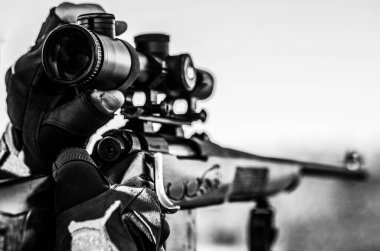 Nişancı hedefte görüldü. Avlanma silahı ve avlanma biçimi olan bir avcı. Hunter nişan alıyor. Siyah ve beyaz.