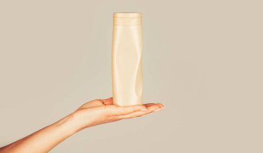 Kozmetik şişeli kadın elleri. Ellerinde saç kremi şişesi var. Kozmetik şişeli kadın eli. Şampuan şişesi elinde. Saç bakımı için jel dağıtıcı.