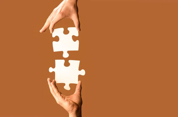 夫婦のパズルを黄色の背景で接続しようとする2つの手 ジグソーパズルをつなぐ手 パズルピースをつなぐ男の手 — ストック写真