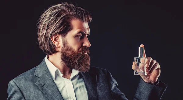 Perfume or cologne bottle and perfumery, cosmetics, scent cologne bottle, male holding cologne. Masculine perfume, bearded man in a suit. Man perfume, fragrance.