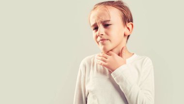 Bir çocukta boğaz ağrısı. Çocuğun boğazı ağrıyor. Çocuklarda soğuk algınlığı belirtileri. Küçük çocuk boğazının ağrıdığını hissediyor. Boğazı ağrıyan küçük bir çocuk. Boğazı ağrıyan hasta çocuk..