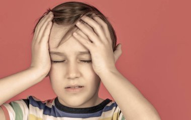 Küçük çocuğun başı ağrıyor. Umutsuzluk, trajedi. Kafasını eliyle tutan üzgün bir çocuğun portresi.