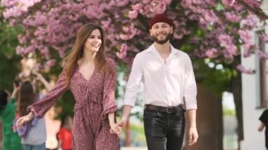 Aile ilişkileri. Eller, bahar, aşk, eller. Sevgililer sakura 'da el ele tutuşur. Genç ve sevgi dolu bir çift el ele tutuşuyor. Birbirine aşık genç bir çift. Erkek kadının elini tutar..