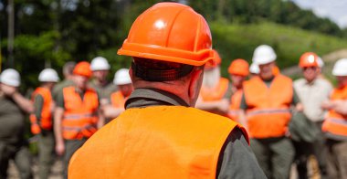 İnşaatçı adam. Miğfer yapımcısı. Bir sürü inşaat işçisi kaskı. Takım iş için hazır. Çelik yelek giyen işçi grubu, güvenlik. İnşa kavramı.