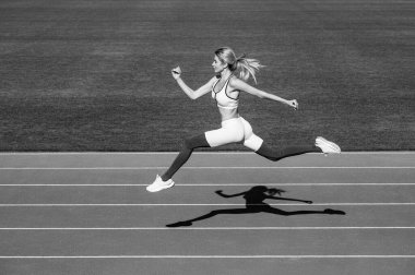 Kaçak. Koşu antrenmanı sırasında profesyonel sporcu. Stadyumda koşan bir kadın. Kadın koşarken. Spor geçmişleri. Siyah ve beyaz.