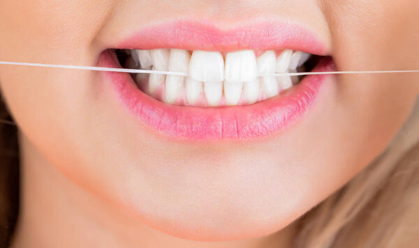 Dental floss. Taking care of teeth. Teeths Flossing. Dental flush - woman flossing teeth. Oral hygiene and health care. Smiling women use dental floss white healthy teeth.
