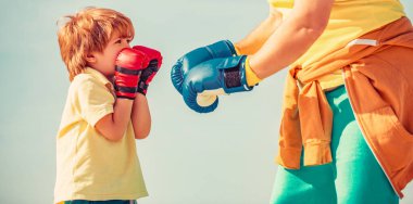 Koçla boks antrenmanında küçük bir çocuk. Sporcu adam kırmızı boks eldivenli küçük çocuğa koçluk yapıyor..