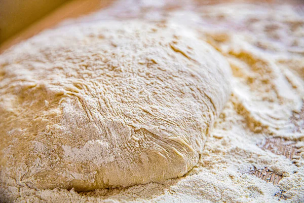 Close-up fermented doughs, homemade. Macro selective focus raw dough texture backdrop. Texture of rolled dough. Background of the dough for baking. Fresh raw dough for pizza or bread baking.