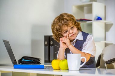 Sıkıcı bir iş. Genç iş adamı. Küçük patron ofiste. Genç iş adamı dizüstü bilgisayar kullanıyor. Ofisteki yakışıklı çocuk. Cidden küçük çocuk işadamı. Eğitim, çocuklar, teknoloji.