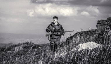 Avcı adam. Silahlı bir erkek. Avlanma silahı ve avlanma biçimi olan bir avcı. Hunter nişan alıyor. İnsan avlanıyor. Av tüfeği. Siyah ve beyaz.