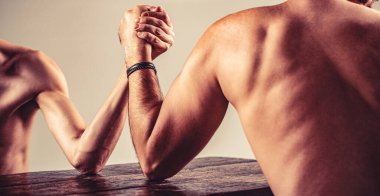 İki adamın elleri birbirine kenetlenmiş bilek güreşi, güçlü ve zayıf, eşit olmayan maç. Bilek güreşi. Güçlü kaslı sakallı adam zayıf bir adamla bilek güreşi yapıyor..