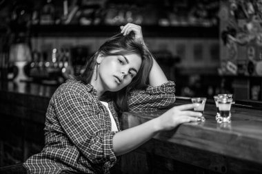 İçki içen kadın. Barda ya da barda alkol bağımlılığı ve alkol konseptiyle izole edilmiş viski bardağı. Siyah ve beyaz.